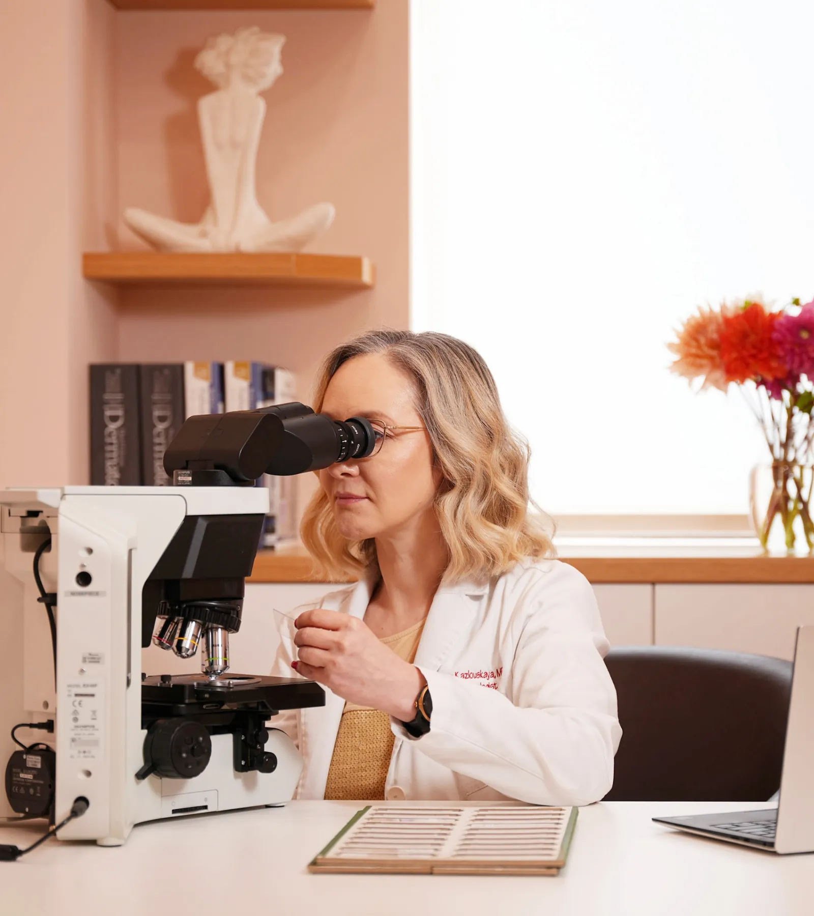 Dr. Viktoryia Kazlouskaya reviewing dermatopathology under a microscope